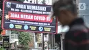 Warga berjalan di dekat spanduk peringatan Zona Merah di RW 004, Kelurahan Cipinang Melayu, Kecamatan Makassar Jakarta, Rabu (27/1/2021). Pemprov DKI Jakarta mencatat sebanyak 54 rukun warga (RW) menjadi zona merah Covid-19 per 21 Januari 2021. (merdeka.com/Iqbal S Nugroho)