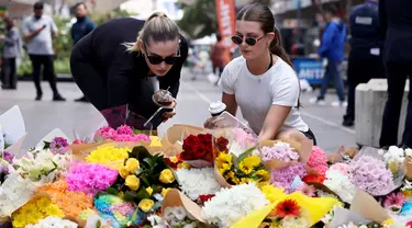 Orang-orang meletakkan bunga di luar pusat perbelanjaan Westfield Bondi Junction di Sydney pada 14 April 2024. (DAVID GRAY/AFP)