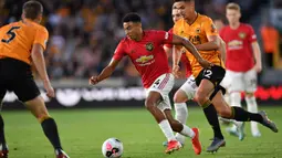 Gelandang Manchester United, Jesse Lingard, berusaha melewati bek Wolverhampton, Ryan Bennett, pada laga Premier League di Stadion Molineux, Wolverhampton, Senin (19/8). Kedua klub bermain imbang 1-1. (AFP/Paul Ellis)