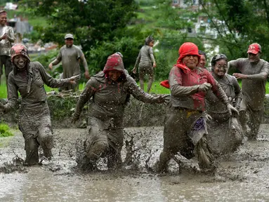 Para petani berlumur lumpur saat bermain pada Hari Padi Nasional di sawah Desa Tokha, Kathmandu, Nepal, Senin (29/6/2020). Para petani di Nepal merayakan Hari Padi Nasional sebagai musim tanam padi tahunan dimulai. (PRAKASH MATHEMA/AFP)