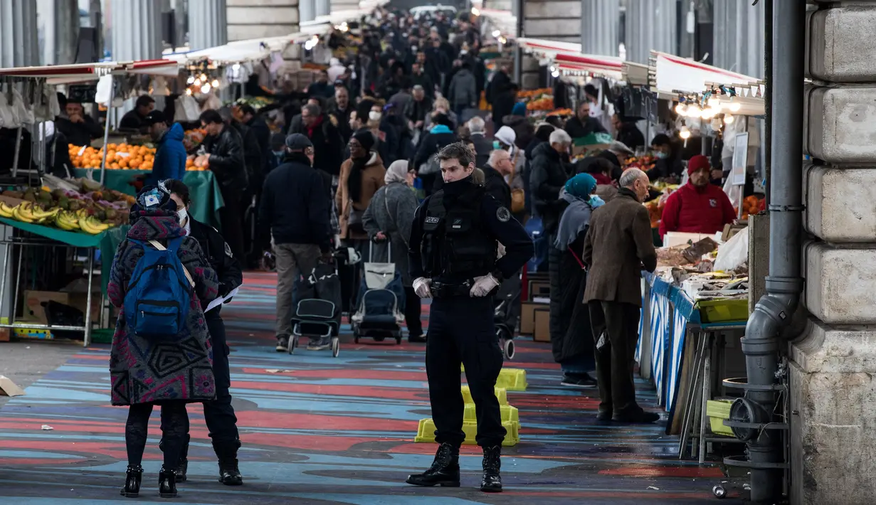 Polisi berjaga saat warga berbelanja ketika lockdown di Barbes Market, Paris, Prancis, Rabu (18/3/2020). Prancis menjadi negara dengan kasus virus corona COVID-19 terbanyak ketujuh di dunia. (JOEL SAGET/AFP)