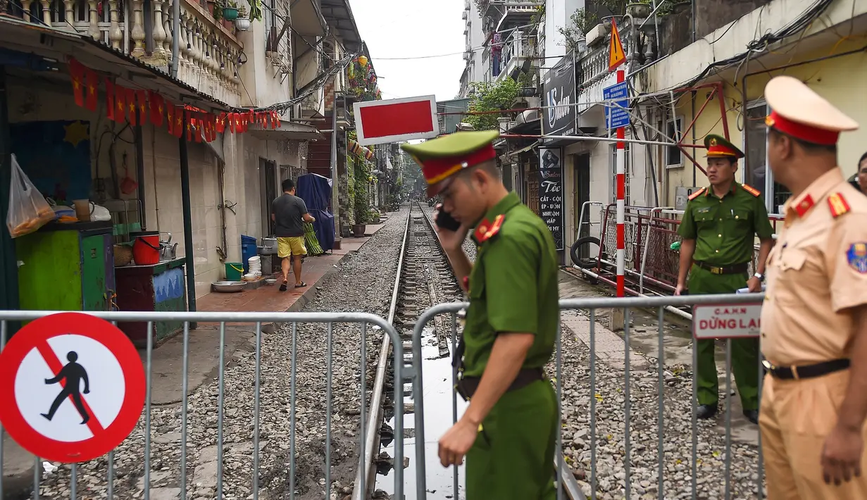 Polisi berjaga dekat barikade rel kereta yang populer sebagai lokasi selfie di Hanoi, Vietnam, Kamis (10/10/2019). Banyak wisatawan duduk di kafe-kafe pinggir rel kereta tersebut sambil menunggu giliran untuk selfie di lintasan. (Nhac NGUYEN/AFP)