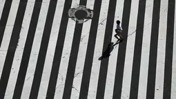 Seorang wanita berlari melintasi Shibuya Crossing yang juga disebut sebagai persimpangan pejalan kaki tersibuk dunia, di Tokyo, 13 Juni 2019. Di Shibuya Crossing ini juga dijadikan lokasi syuting dari film Fast & Farious: Tokyo Drift. (AP Photo/Jae C. Hong)