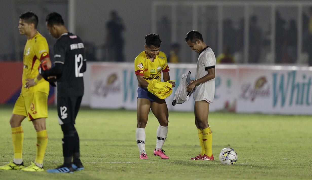 Gelandang Madura United, Andik Vermansah, bertukar jersey dan celana dengan gelandang Bhayangkara FC, Wahyu Suboseto, pada laga Liga 1 2019 di Stadion Madya, Jakarta, Senin (5/8). Kedua tim bermain imbang 1-1. (Bola.com/M iqbal Ichsan)