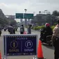 Sejumlah petugas di Simpang Gadog, Bogor, Jawa Barat memerhatikan pelat nomor kendaraan yang melintas menuju arah Puncak, Minggu (5/9/2021) pagi. (Liputan6.com/Achmad Sudarno)