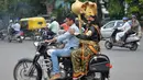 Pengendara motor tanpa helm membonceng seniman berpakaian seperti "Yamaraj" (R), dewa kematian Hindu saat  kampanye 'Road Safety Week' yang diselenggarakan oleh polisi lalu lintas di Bangalore (10/7). (AFP Photo/Manjunath Kiran)