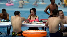 Sejumlah orang bermain catur di dalam kolam renang saat cuaca panas melanda wilayah Chongqing di Tiongkok, Rabu (2/8). Tiongkok saat ini dilaporkan sedang mengalami cuaca panas dengan suhu di beberapa daerah hampir mencapai 40 derajat celcius. (STR / AFP)