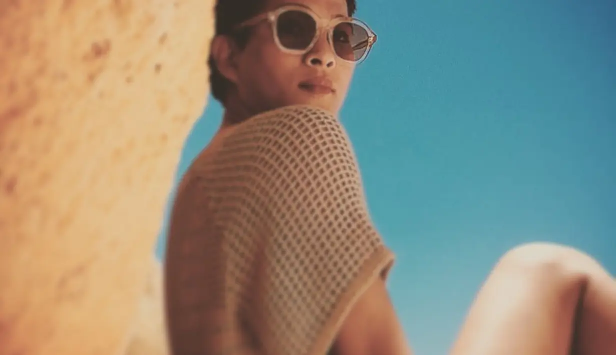Menyatu dengan warna pasir dan bebatuan, outfit warna nude juga menjadi pilihan tepat untuk bersantai di pantai. Seperti Oscar yang memilih blouse rajut serta frame kacamata hitam senada untuk tampilan monokrom yang manis. (Foto: Instagram/oscarlawalata)