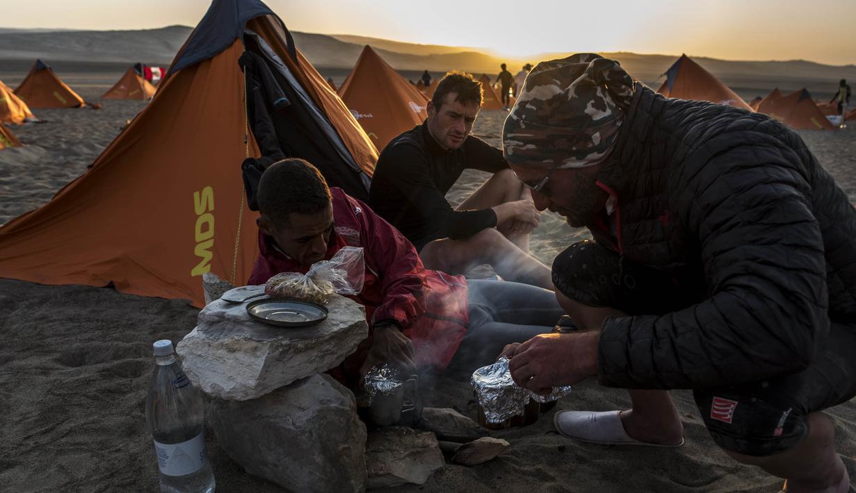 Para peserta mempersiapkan makan saat mengikuti lomba marathon sejauh 250 kilometer di Gurun Ica, Kamis (30/11/2017). Marathon yang terbagi dalam enam tahapan ini diprediksi akan berakhir pada 4 Desember. (AFP/Jean-Philippe Ksiazek)