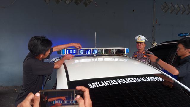 Pemasangan kaca film pada lampu rotator mobil Satlantas Polresta Bandar Lampung. Foto : (Liputan6.com/Ardi)