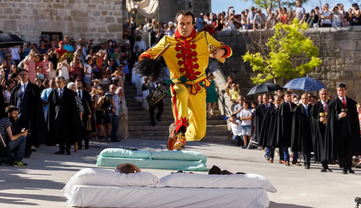 Warga menyaksikan pria berkostum setan melompati bayi-bayi yang terlentang di atas matras selama festival El Colacho di desa Castrillo de Murcia, Minggu (18/6). Sampai saat ini, belum ada laporan terjadi luka-luka di antara para bayi. (CESAR MANSO/AFP)