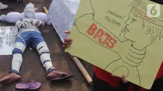 Pengunjuk rasa dari Serikat Rakyat Miskin Indonesia menggelar aksi teatrikal menolak kenaikan iuran BPJS Kesehatan di depan Kompleks Parlemen, Jakarta, Senin (11/11/2019). Massa meminta Presiden Joko Widodo atau Jokowi mencabut Perpres Nomor 75 Tahun 2019. (Liputan6.com/JohanTallo)