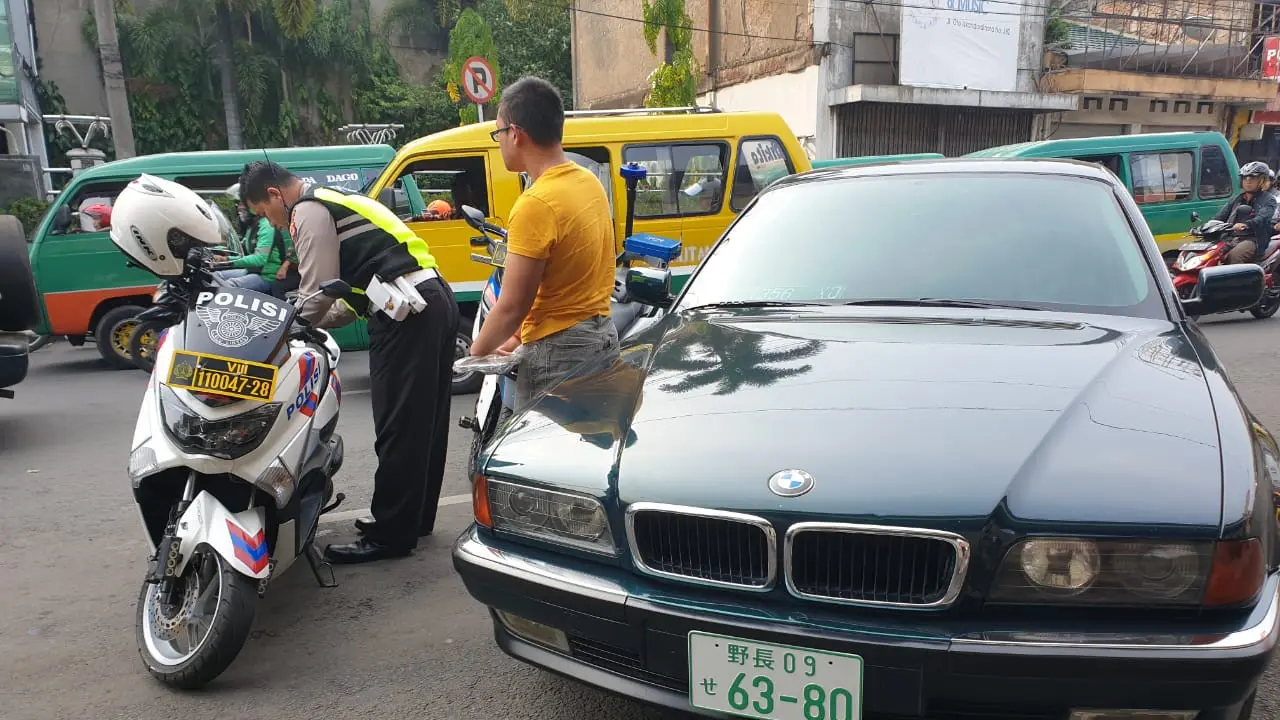 Polisi tilang pengendaran BMW yang menggunakan plat nomor Jepang.