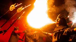 Seorang peserta bertopeng iblis menyemburkan api saat Festival Correfoc di Palma de Mallorca, Spanyol, Minggu (21/1). Dalam festival ini peserta bergerak ke jalanan dan menakut-nakuti warga dengan api dan kembang api. (AFP PHOTO/JAIME REINA)