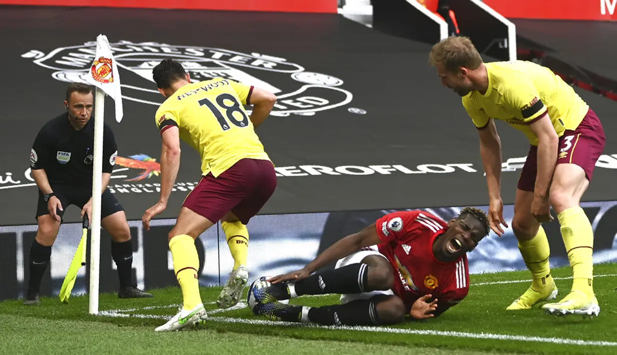 Pemain Manchester United Paul Pogba (tengah) berbaring kesakitan di lapangan saat melawan Burnley pada pertandingan Liga Inggris di Stadion Old Trafford, Manchester, Inggris, Minggu (18/4/2021). Manchester United menang 3-1. (Gareth Copley/Pool via AP)