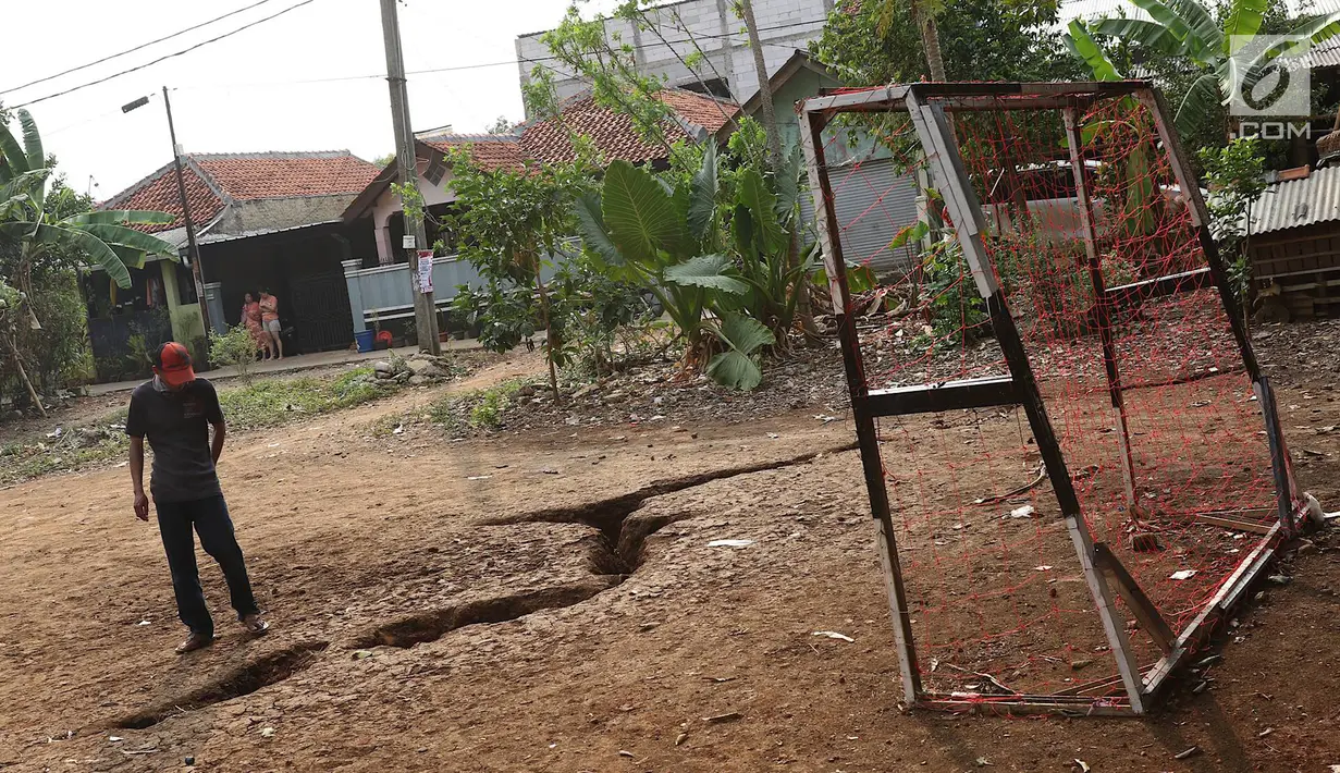 Warga mengamati tanah terbelah di lapangan RT 02 RW 02 Kampung Pedurenan, Kelurahan Cisalak Pasar, Cimanggis, Depok, Jawa Barat, Senin (22/10). Tanah terbelah tersebut terjadi saat hujan deras. (Liputan6.com/Immanuel Antonius)