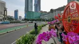 Warga berfoto di depan ornamen dengan nuansa Imlek di kawasan Bundaran HI, Jakarta, Sabtu (29/1/2022). Ornamen yang didominasi warna merah dan emas ini dipasang dalam rangka menyambut perayaan Tahun Baru Imlek 2573, yang jatuh pada 1 Februari mendatang. (Liputan6.com/Herman Zakharia)