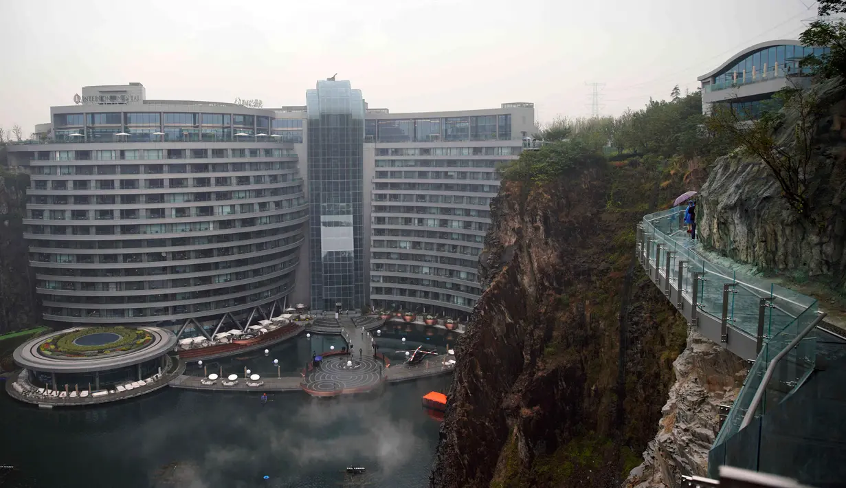Pengunjung berjalan dekat Hotel Intercontinental Shanghai Wonderland di distrik Songjiang, Shanghai, 15 November 2018. China membuat sebuah hotel mewah pertama di dunia pada sebuah lokasi bekas lubang pertambangan yang amat dalam. (AP Photo)