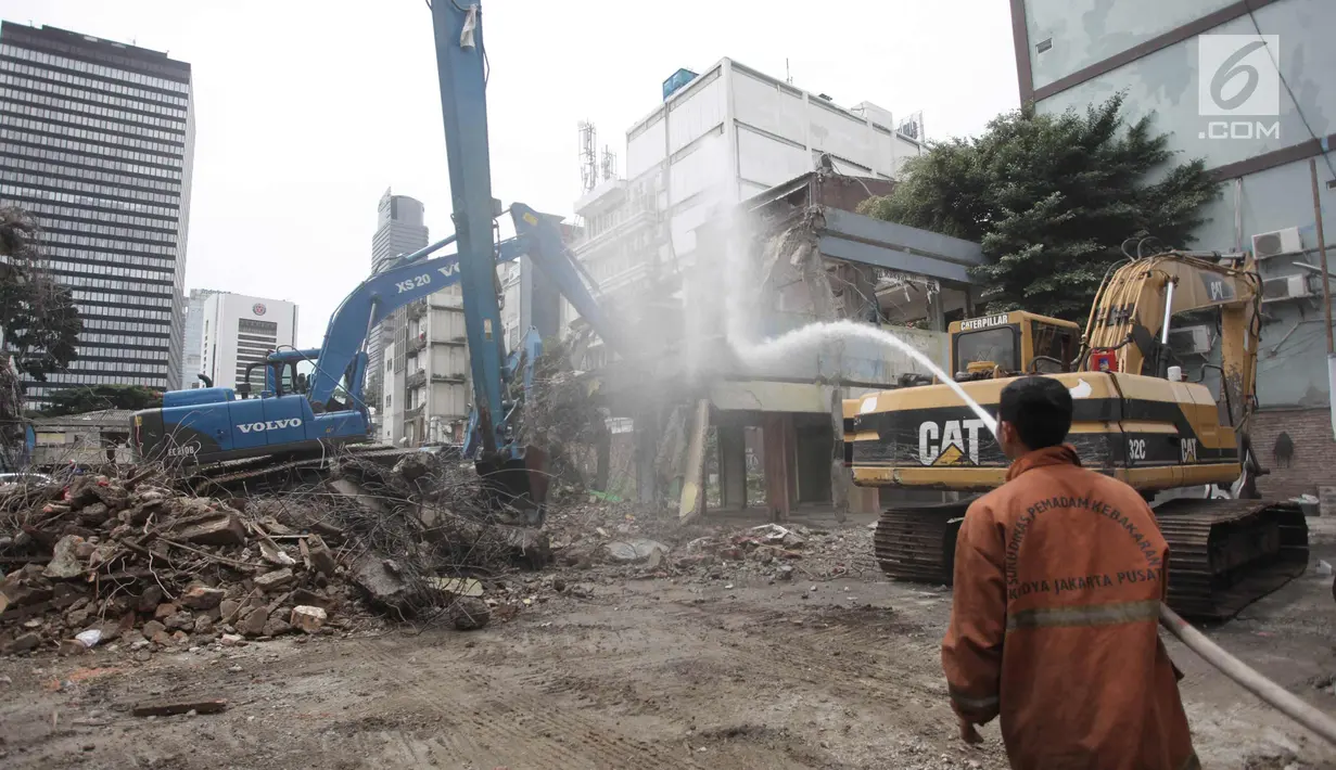 Petugas menyemprotkan air ke bangunan yang dirobohkan di kompleks Pasar Blora, Jakarta, Kamis (25/1). Lahan milik PD Pasar Jaya itu rencananya akan dibangun pasar kembali. (Liputan6.com/Arya Manggala)