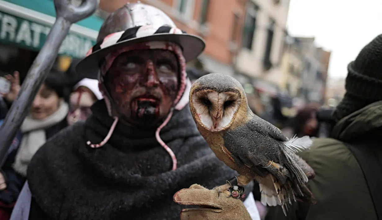 Seorang peserta membawa burung hantu saat menjelang pembukaan Carnival of Venice 2017, Italia (11/2). Pembukaan karnaval ditandai dengan dimulainya acara pertama Nordic Walkin Carnival4 pada Sabtu (11/2) pukul 8.30 waktu setempat. (AFP/Marco Bertorello)