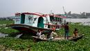 Orang-orang menonton feri yang diselamatkan setelah kecelakaan di Sungai Shitalakshya di Narayanganj, Bangladesh (21/3/2022). Feri ML Afsar Uddin tenggelam di sungai setelah ditabrak kapal kargo. (AFP/Munir uz Zaman)