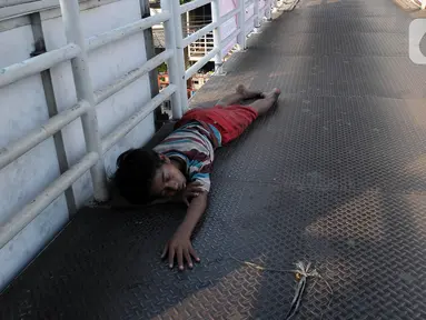 Seorang anak tertidur di Jembatan Penyebrangan Orang (JPO) kawasan Glodok, Jakarta Sabtu (22/7/2023). Berdasarkan data penyandang masalah kesejahteraan sosial anak jalanan yang dipublikasikan oleh Kementerian Sosial pada tahun 2012, jumlah anak jalanan di Indonesia mencapai angka 135.598 ribu jiwa. (merdeka.com/Imam Buhori)