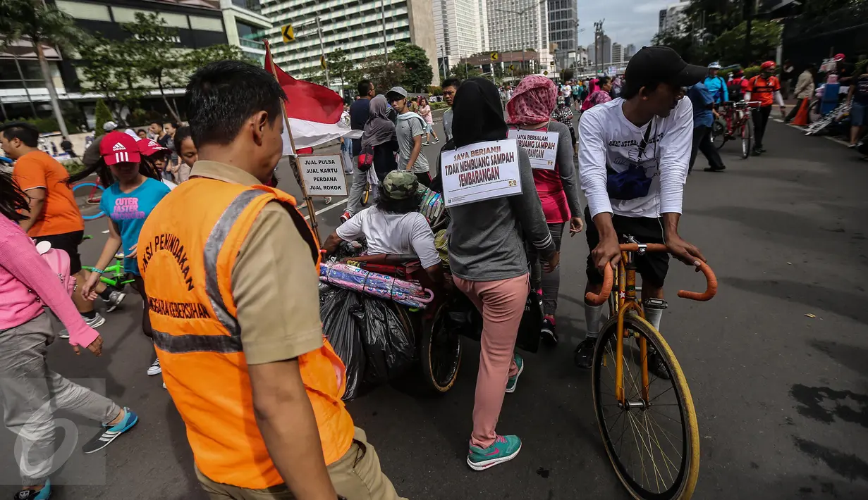 Pengunjung car free day (CFD) berkeliling memunguti sampah sampah di kawasan Bundaran HI, Jakarta, Minggu (29/1). Mereka juga mengenakan papan bertuliskan "Saya Berjanji Tidak Membuang Sampah Sembarangan" (Liputan6.com/Faizal Fanani)