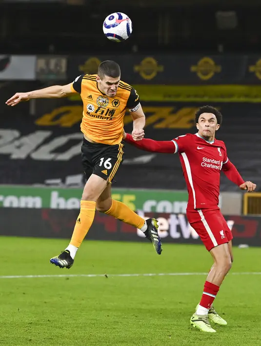 Pemain Wolverhampton Wanderers Conor Coady menyundul bola disaksikan pemain Liverpool Trent Alexander-Arnold pada pertandingan Liga Inggris di Stadion Molineux, Wolverhampton, Inggris, Senin (15/3/2021). Liverpool menang 1-0. (AP Photo/Paul Ellis,Pool)