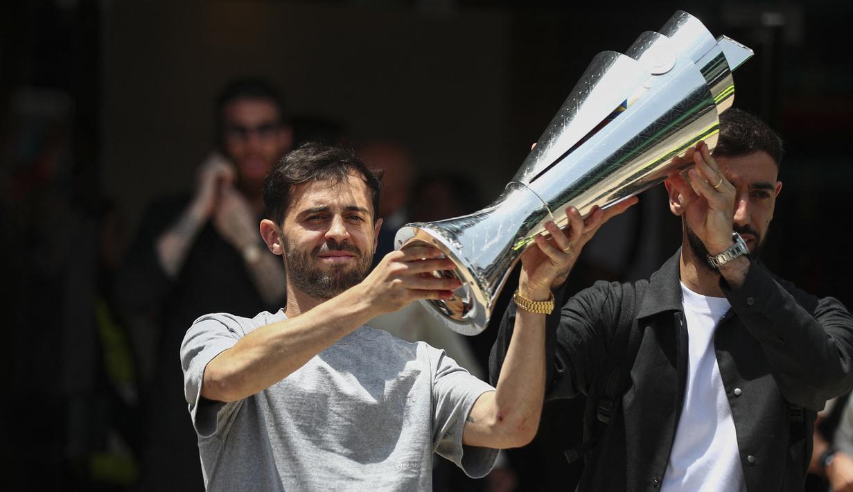 Pemain Timnas Portugal, Bruno Fernandes (kiri) dan Bernardo Silva mengangkat trofi juara Nations League 2025 setibanya di Bandara Lisbon, Portugal, Senin (09/06/2025) waktu setempat. (AFP/Carlos Costa)