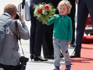 Putra PM Kanada Justin Trudeau, Hadrien, mengarahkan buket bunga kepada fotografer setibanya di Hamburg, Jerman, Kamis (6/7). PM Kanada membawa istri, Sophie Gregoire-Trudeau, dan putranya, Hadrien untuk menghadiri KTT G20. (AP Photo/Markus Schreiber)