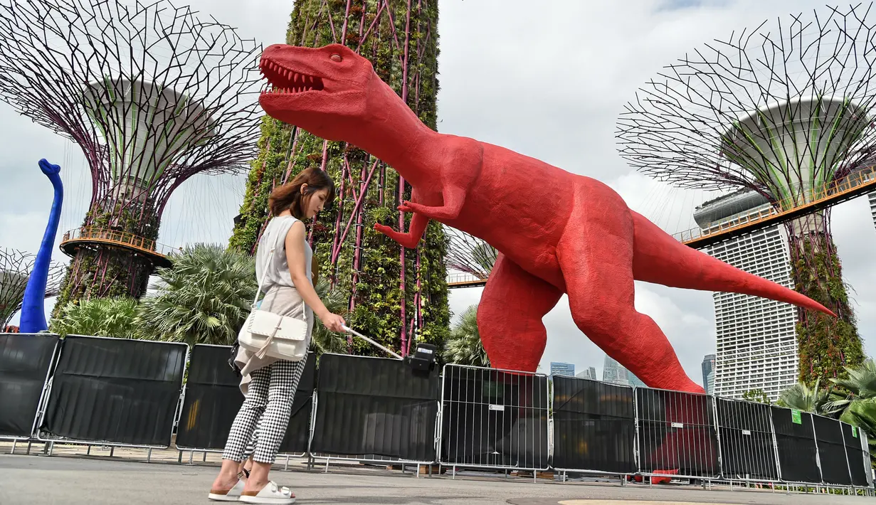 Pengunjung mengambil gambar patung dinosaurus yang terpajang di Gardens by the Bay, Singapura, Senin (28/2). Rencananya akan dipamerkan sebanyak 11 dinosaurus beraneka warna untuk merayakan Festival Anak di Singapura. (AFP PHOTO / Roslan RAHMAN)