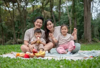 Keluarga bahagia sedang piknik di taman yang rindang, menikmati akhir pekan bersama. (Depositphoto/BongkarnGraphic)