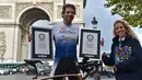 Pembalap sepeda Inggris, Mark Beaumont (34) berpose dengan sertifikat Guinness World Records setibanya di Arc de Triomphe, Paris, setelah menyelesaikan tur keliling dunia dalam waktu 78 hari, Senin (18/9). (CHRISTOPHE ARCHAMBAULT / AFP)