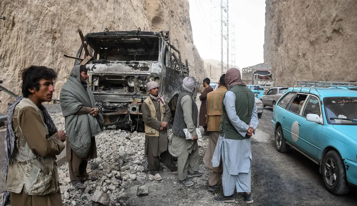 Warga Afghanistan memeriksa sisa-sisa truk yang hangus di sepanjang jalan raya, menyusul gempa bumi di Tang-e Tashkurgan, distrik Khulm, provinsi Samangan, pada Senin 3 November 2025. Gempa ini dikategorikan pada tingkat peringatan oranye, yang menandakan kemungkinan besar terjadinya korban jiwa dalam jumlah signifikan. (Atif Aryan/AFP)