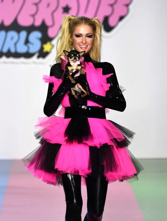 Paris Hilton membawa anjing saat tampil dalam Christian Cowan x The Powerpuff Girls Fashion Show, Los Angeles, AS, Jumat (8/3). Anjing tersebut merupakan peliharaannya yang bernama Diamond Baby. (Frazer Harrison/Getty Images North America/AFP)