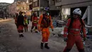 Anggota tim penyelamat Inggris melihat-lihat bangunan yang hancur di Antakya, Turki, 9 Februari 2023. Tim penyelamat melakukan upaya terakhir pada Kamis untuk menemukan korban selamat dari bencana gempa bumi di Turki dan Suriah yang membuat banyak komunitas tidak dapat dikenali oleh penghuninya. (AP Photo/Khalil Hamra)
