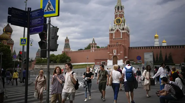 Orang-orang berjalan di depan Red Square yang ditutup dengan Tembok Kremlin dan Menara Spasskaya di latar belakang di Moskow, Rusia, Selasa, 27 Juni 2023. (AP Photo/Alexander Zemlianichenko)