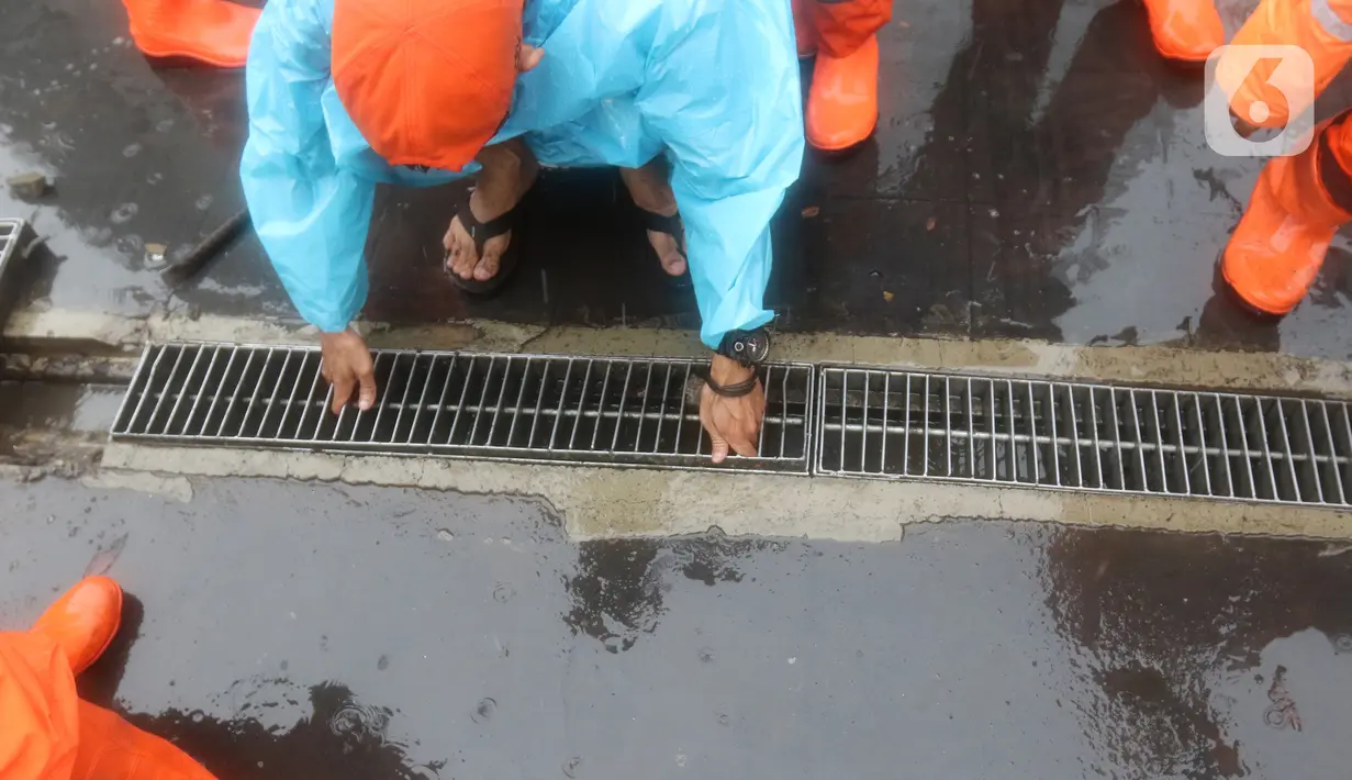 Petugas Penanganan Prasarana dan Sarana Umum (PPSU) membersihkan saluran air di kawasan Gelora Bung Karno, Jakarta, Selasa (17/12/2019). Petugas PPSU membersikan saluran air saat terjadi genangan usai hujan deras mengguyur Jakarta. (Liputan6.com/Herman Zakharia)