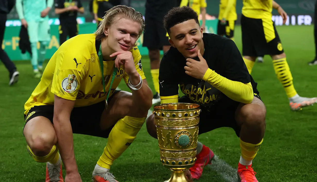 Striker Borussia Dortmund, Erling Haaland (kiri) dan gelandang Jadon Sancho berfoto dengan trofi juara DFB Pokal usai menang 4-1 atas RB Leipzig dalam laga final DFB Pokal 2020/2021 di Olympiastadion, Berlin, Kamis (13/5/2021). (AFP/Annegret Hilse/Pool)
