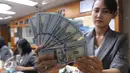 Petugas menunjukkan mata uang Dolar Amerika di toko penukaran uang di Jakarta, Selasa (7/6). Dolar AS kembali melemah terhadap rupiah. Mata uang Paman Sam ini bergerak dikisaran Rp 13.300. (Liputan6.com/Angga Yuniar)