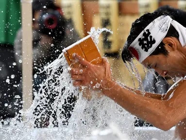 Penganut agama Shinto melakukan mandi air dingin di Kuil Kanda, Tokyo, Jepang (13/1). Mandi air dingin ini merupakan ritual yang digelar untuk menyucikan tubuh dan jiwa mereka. (AFP Photo/Toshifumi Kitamura)