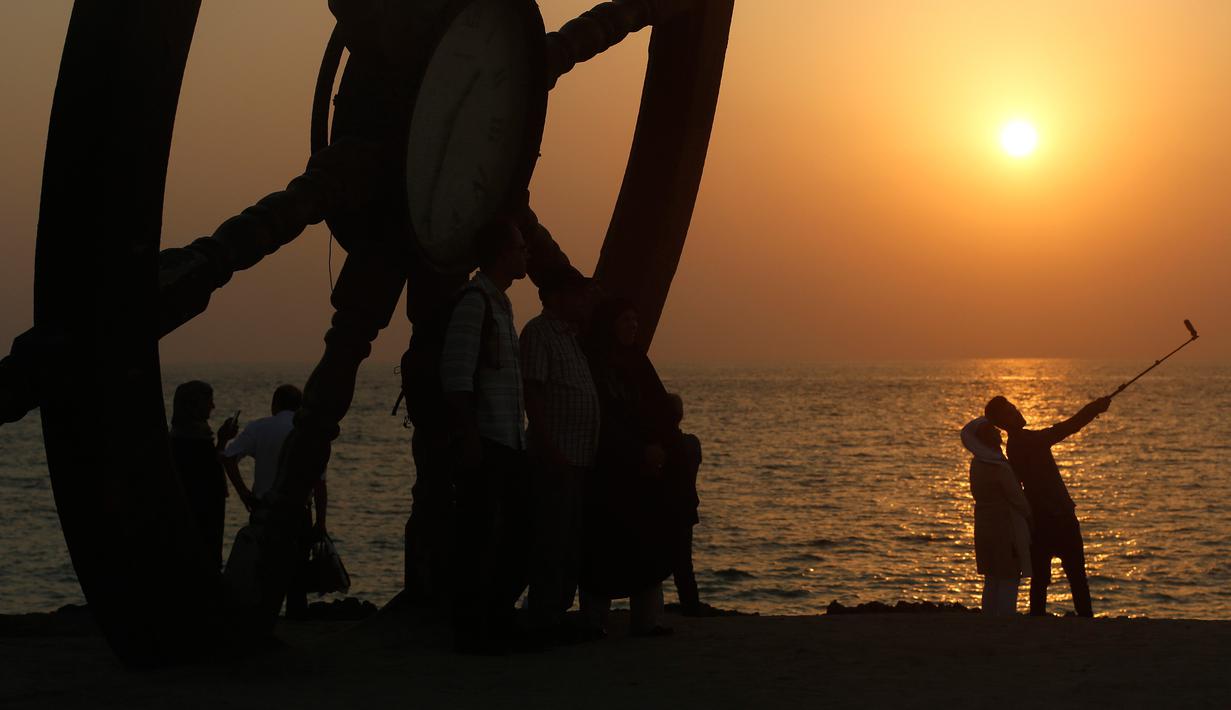 Turis mengabadikan gambar saat matahari tenggelam atau sunset di pinggir laut, Pulau Kish, Iran, 1 November 2016. Kish sudah menarik 1,8 juta pengunjung per tahun, dari 2,2 juta pada 2009 menjadi 5,2 juta pada 2015. (Atta Kenare/AFP)