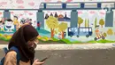 Anak sekolah melintas di depan mural dan akses khusus pejalan kaki di Jalan Darul Maarif, Jakarta Selatan, Rabu (11/3/2020). PT MRT Jakarta berkolaborasi dengan ITDP menata jalan-jalan sekitar stasiun untuk meningkatkan aksesibilitas warga sekitar. (Liputan6.com/Immanuel Antonius)