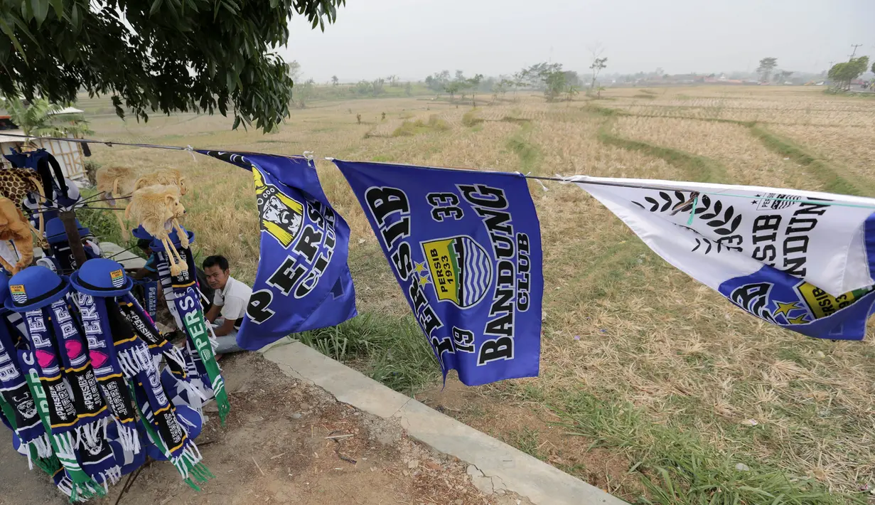 Seorang pedagang atribut santai menunggu pembeli dagangannya di Stadion Si Jalak Harupat, Bandung, Sabtu (24/10/2015). (Bola.com / Nicklas Hanoatubun)