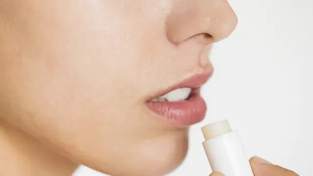 Seorang perempuan sedang mengaplikasikan lip balm di bibirnya (Foto Dok: Freepik/rawpixel.com)