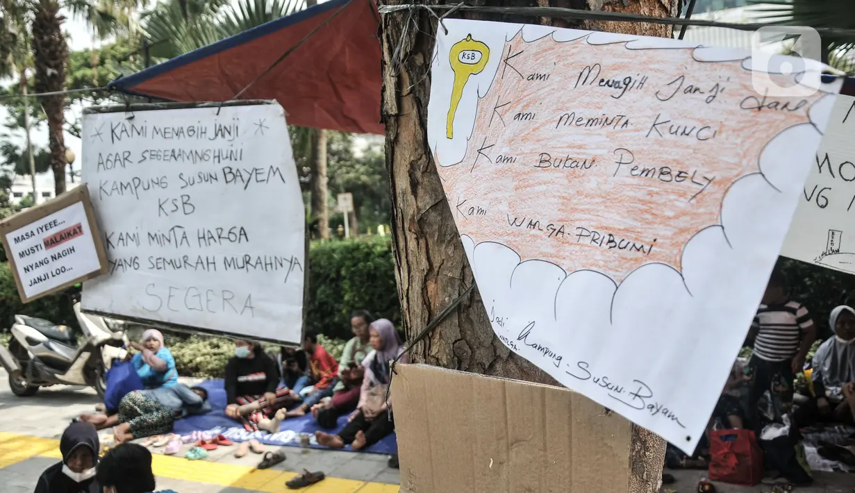 Warga korban gusuran Kampung Bayam mendirikan tenda darurat saat menggelar aksi di depan Balai Kota, Jakarta, Senin (5/12/2022). Dengan membawa terpal dan perabotan rumah tangga, puluhan korban gusuran Kampung Bayam kembali membangun tenda darurat di depan Balai Kota untuk menuntut PT Jakarta Propertindo (JakPro) segera menyerahkan kunci hunian Kampung Susun Bayam (KSB) serta memberikan harga sewa yang murah. (merdeka.com/Iqbal S. Nugroho)
