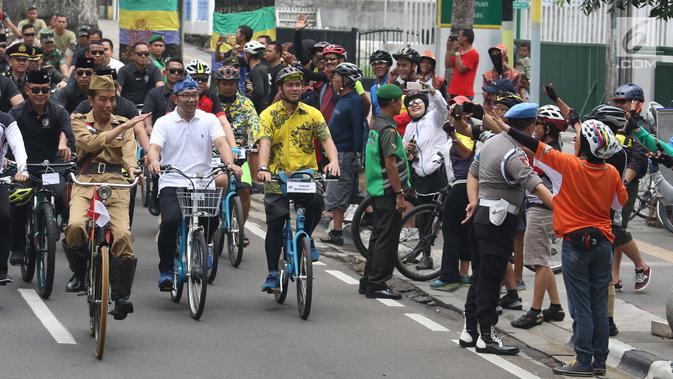 Presiden Joko Widodo atau Jokowi menyapa warga saat mengikuti Bandung Lautan Sepeda, Sabtu (10/11). Jokowi berpakaian khas Sutomo atau Bung Tomo dalam kegiatan tersebut. (Liputan6.com/Angga Yuniar)