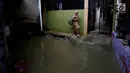 Seorang anak melintasi banjir di permukiman Jati Padang, Jakarta, Kamis (30/11). Banjir yang terjadi tersebut akibat tanggul darurat di Kali Pulo jebol karena genangan air yang cukup deras dan membanjiri Permukiman Sekitar. (Liputan6.com/Johan Tallo)