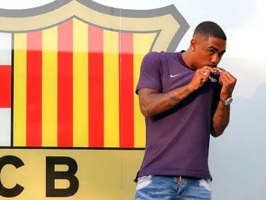 Pesepakbola muda Brasil, Malcom Filipe Silva de Oliveira mencium jersey berlogo Barcelona setibanya di stadion Camp Nou, Selasa (24/7). Barcelona telah membajak Malcolm yang selangkah lagi berkostum AS Roma. (AP Photo/Manu Fernandez)