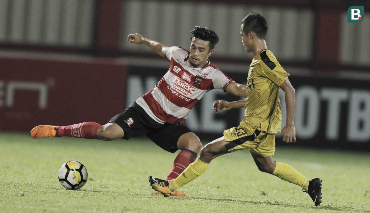 Bek Madura United, Beny Wahyudi, berusaha melewati Gelandang Bhayangkara FC, Wahyu Suboseto, pada laga Liga 1 di Stadion PTIK, Jakarta, Kamis, (07/6/2018). Bhayangkara FC menang 1-0 atas Madura United. (Bola.com/M Iqbal Ichsan)